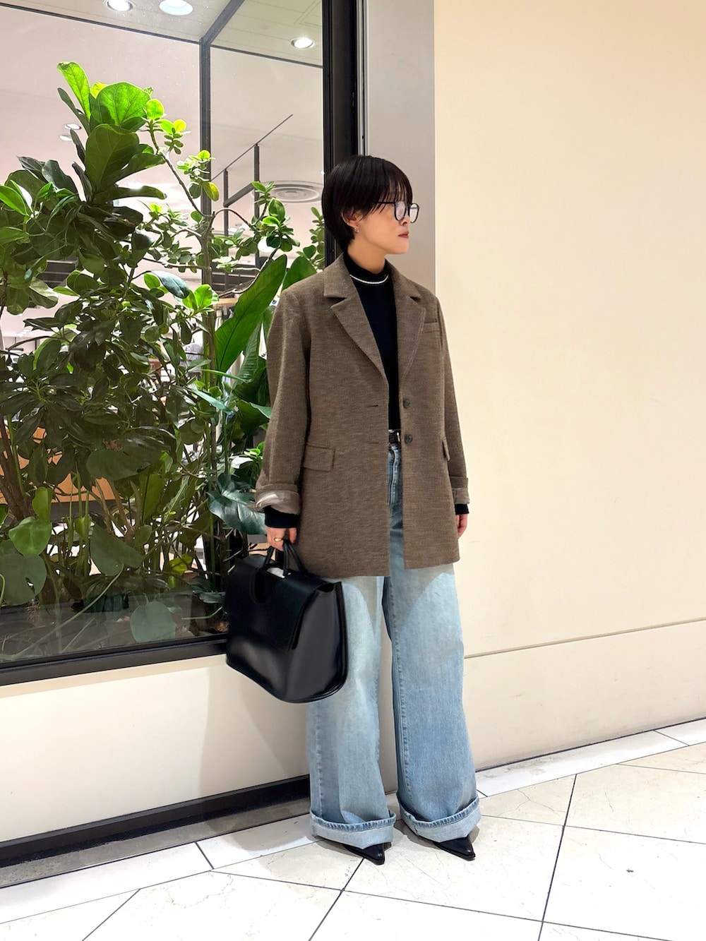 ブルー系のデニムパンツ、ブラック系のハンドバッグ、グリーン系のその他アウターを着用したレディースの秋コーディネートの2枚目の写真