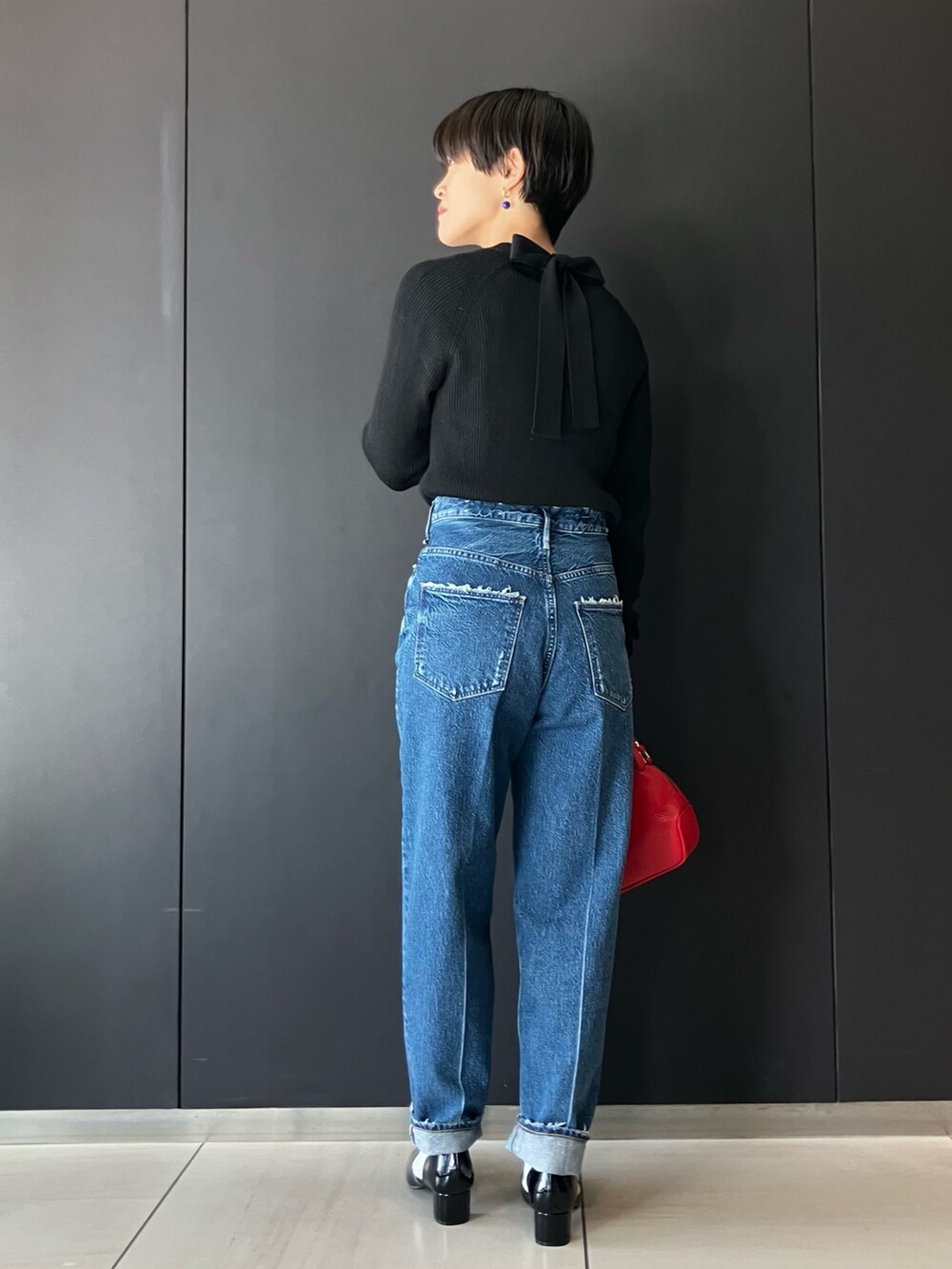 ブラック系のニット/セーター、ブルー系のデニムパンツ、ブラック系のパンプスを着用したレディースの冬コーディネートの2枚目の写真