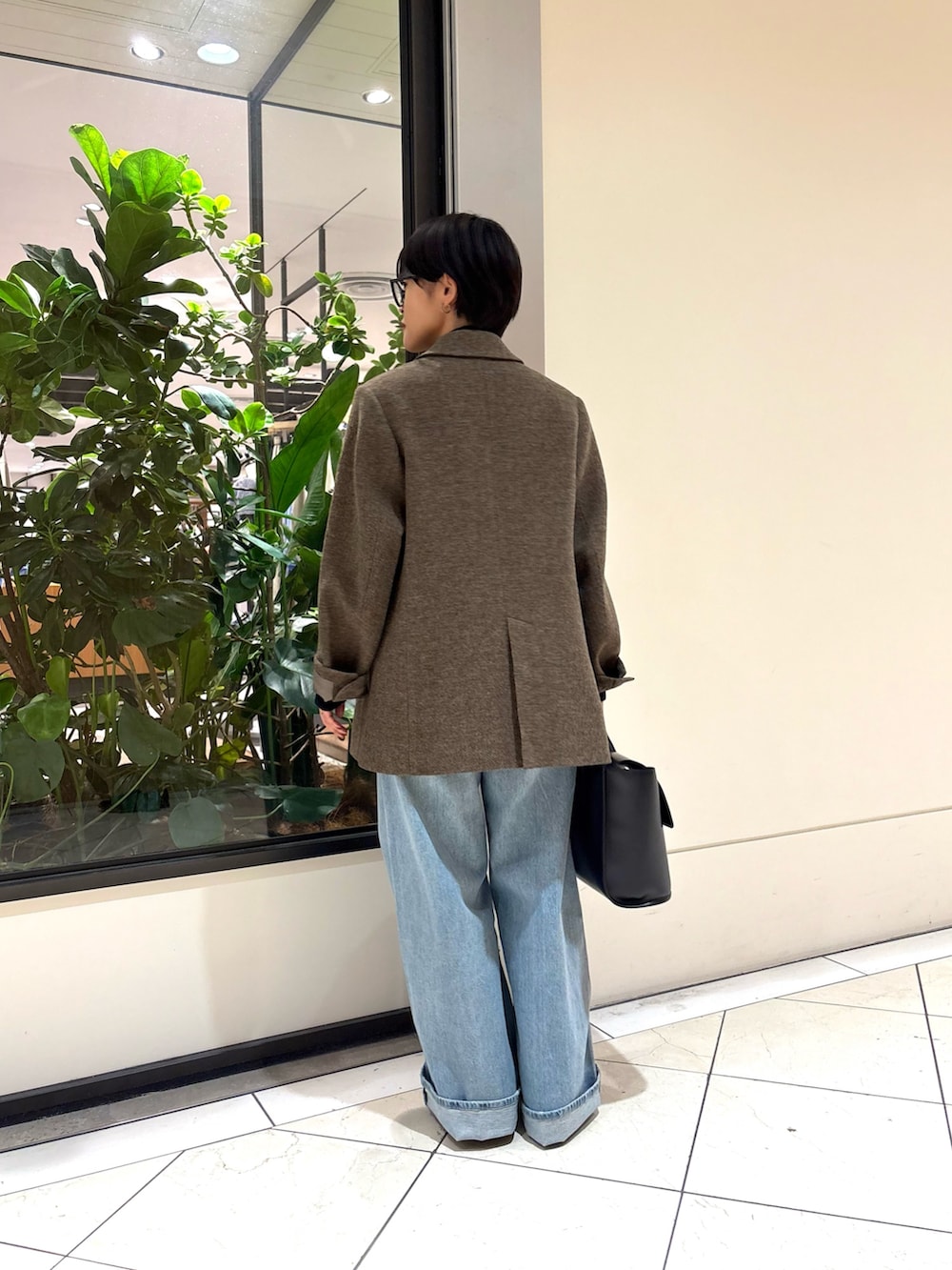 ブルー系のデニムパンツ、ブラック系のハンドバッグ、グリーン系のその他アウターを着用したレディースの秋コーディネートの4枚目の写真