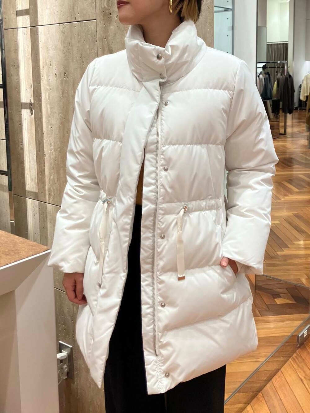 ホワイト系のダウンジャケット/コート、オレンジ系のニット/セーター、ブラック系のその他パンツを着用したレディースの冬コーディネートの5枚目の写真