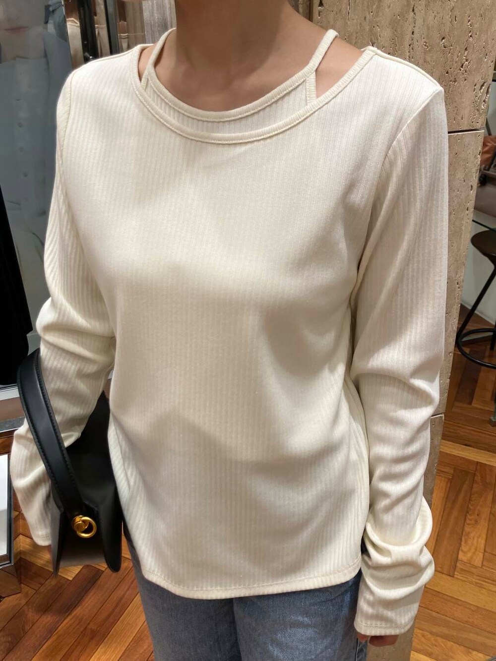 ブラック系のハンドバッグ、ホワイト系のTシャツ/カットソー、ブルー系のデニムパンツを着用したレディースの冬コーディネートの4枚目の写真
