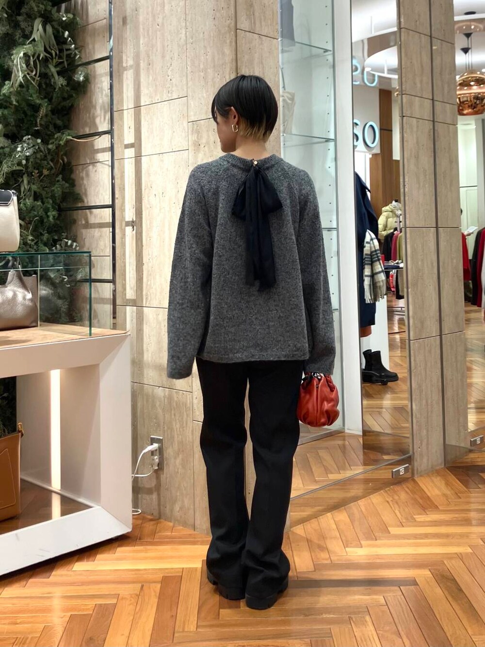 ブラック系のその他パンツ、グレー系のニット/セーター、レッド系のショルダーバッグを着用したレディースの冬コーディネートの2枚目の写真