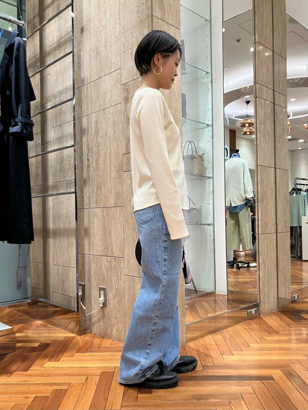 ブラック系のハンドバッグ、ホワイト系のTシャツ/カットソー、ブルー系のデニムパンツを着用したレディースの冬コーディネートの2枚目の写真