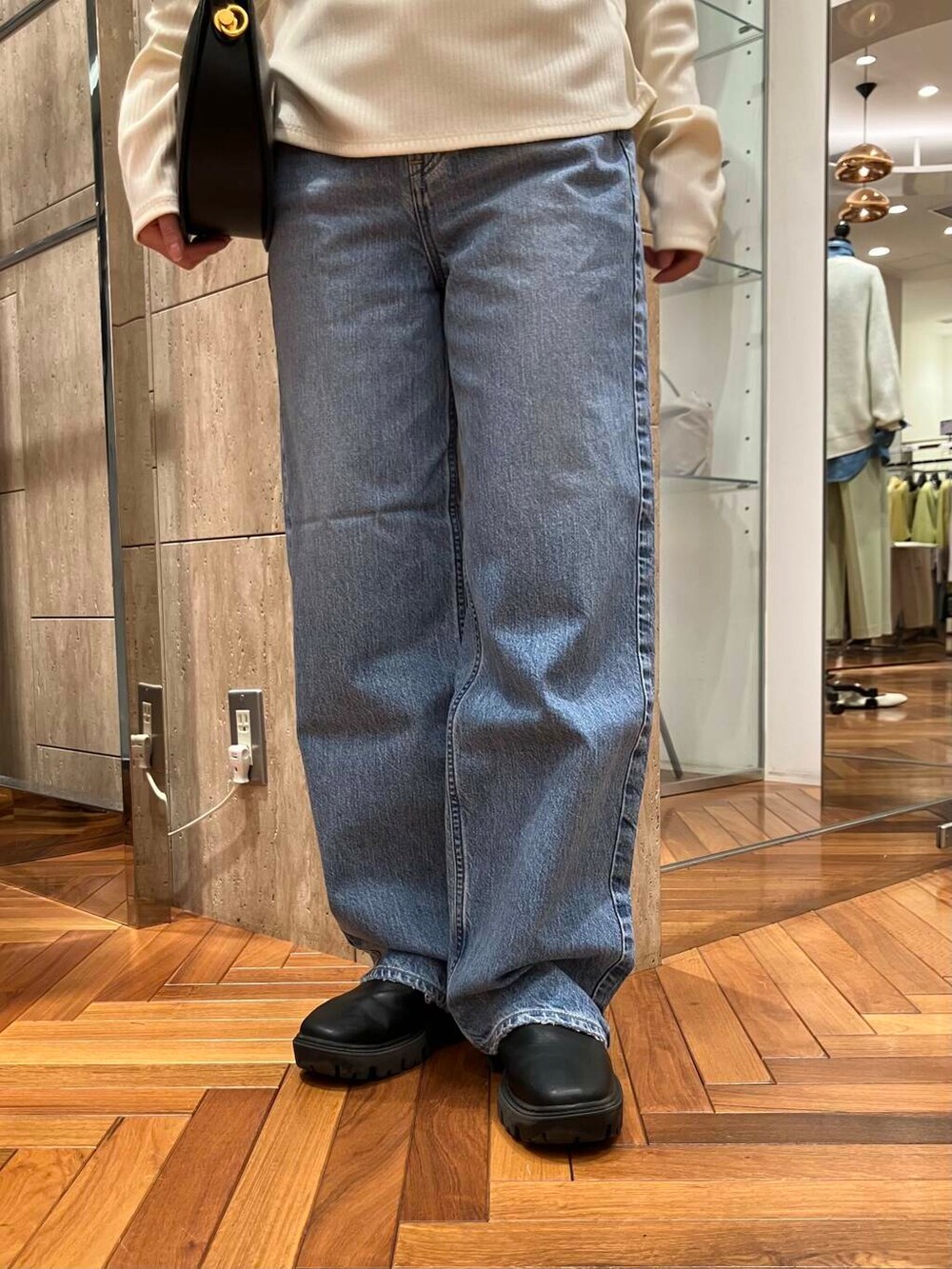 ブラック系のハンドバッグ、ホワイト系のTシャツ/カットソー、ブルー系のデニムパンツを着用したレディースの冬コーディネートの5枚目の写真
