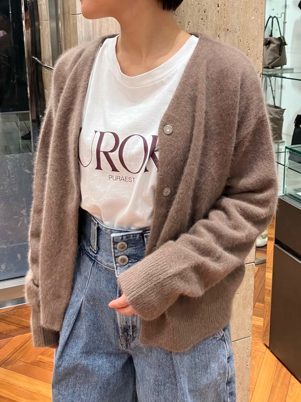 ブルー系のデニムパンツ、ホワイト系のTシャツ/カットソー、イエロー系のカーディガン/ボレロを着用したレディースの秋コーディネートの3枚目の写真