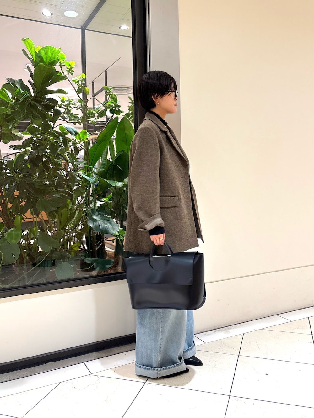 ブルー系のデニムパンツ、ブラック系のハンドバッグ、グリーン系のその他アウターを着用したレディースの秋コーディネートの3枚目の写真