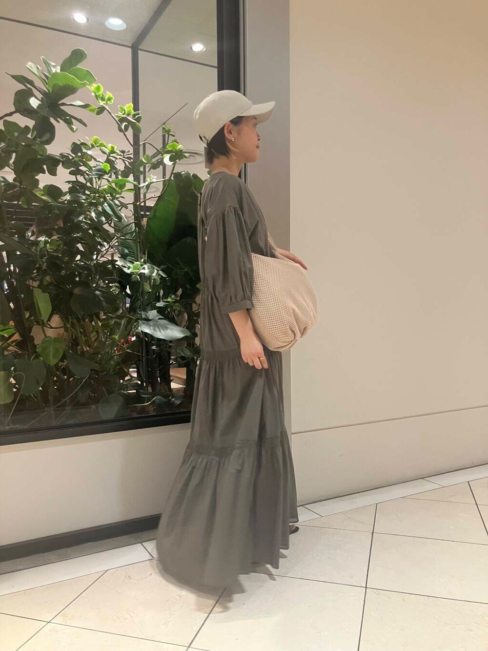 グリーン系のワンピース、ブラウン系のトートバッグ、グリーン系のタンクトップを着用したレディースの春コーディネートの3枚目の写真