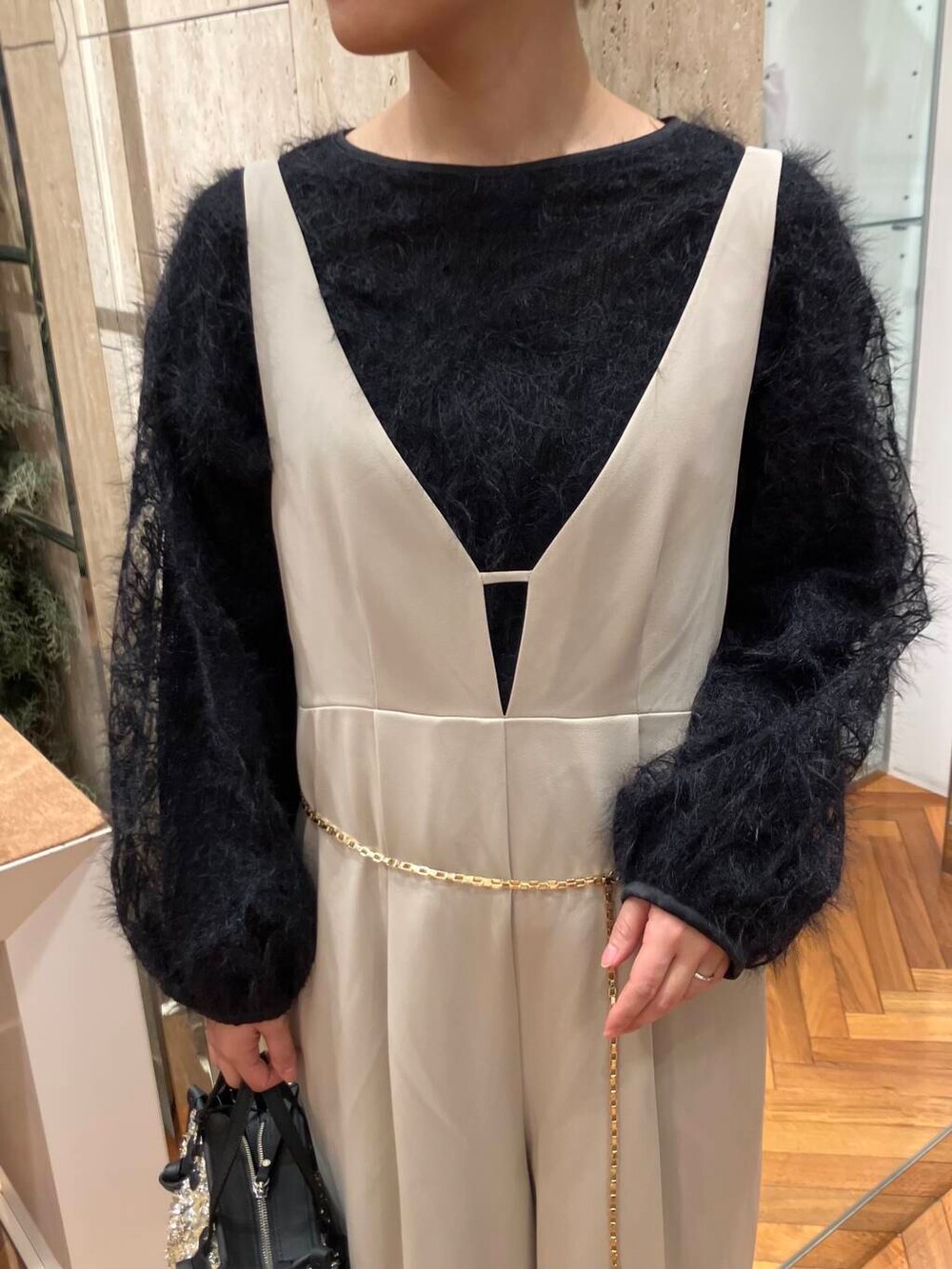 イエロー系のハンドバッグ、ブラック系のシャツ/ブラウス、ベージュ系のサロペット/オーバーオールを着用したレディースの冬コーディネートの2枚目の写真