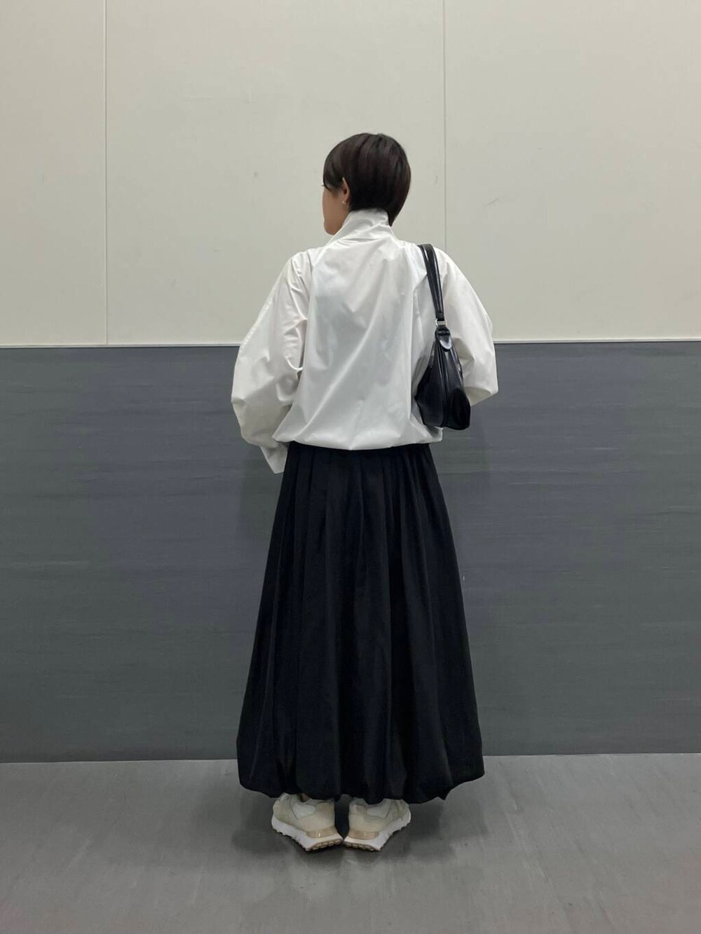 ホワイト系のスニーカー、ブラック系のスカート、ホワイト系のブルゾンを着用したレディースの秋コーディネートの3枚目の写真