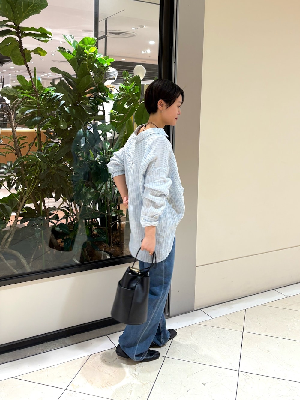 ブルー系のシャツ/ブラウス、ブルー系のデニムパンツ、ブラック系のハンドバッグを着用したレディースの春コーディネートの2枚目の写真