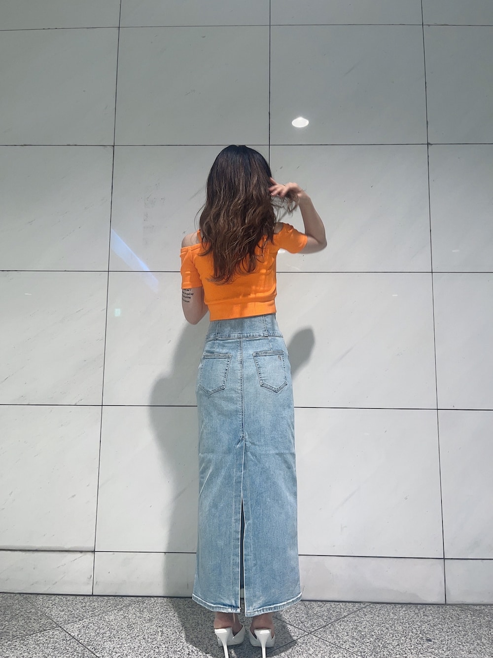 オレンジ系のTシャツ/カットソー、ブルー系のデニムスカート、ホワイト系のパンプスを着用したレディースの夏コーディネートの3枚目の写真