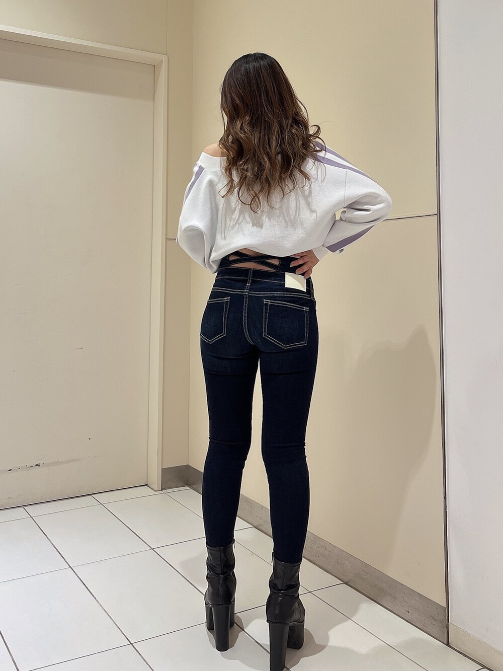 ホワイト系のニット/セーター、ブルー系のデニムパンツ、ブラック系のブーツを着用したレディースの冬コーディネートの2枚目の写真