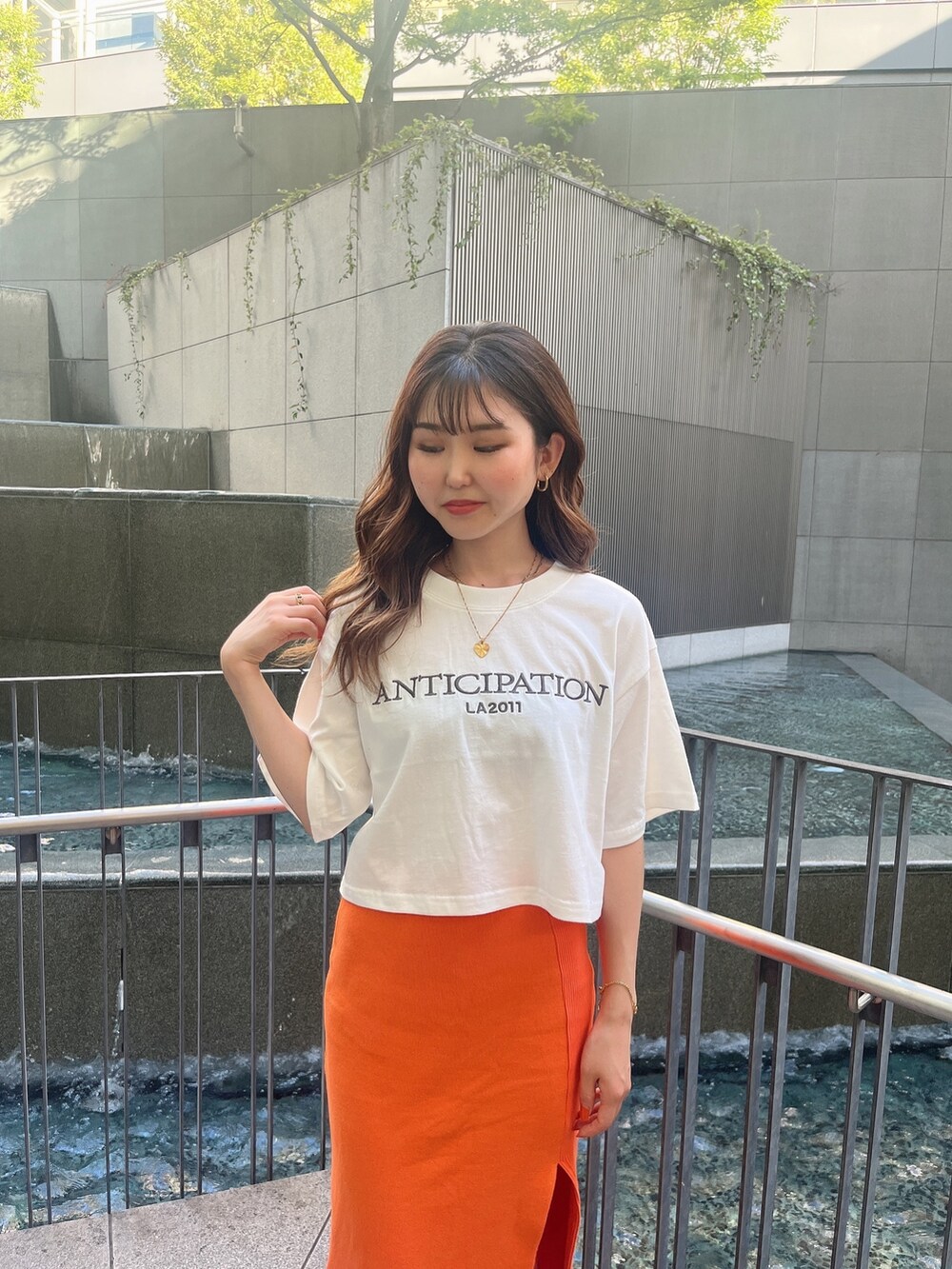 ホワイト系のTシャツ/カットソー、オレンジ系のスカート、ホワイト系のパンプスを着用したレディースの夏コーディネートの3枚目の写真