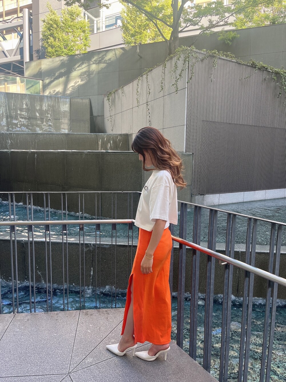 ホワイト系のTシャツ/カットソー、オレンジ系のスカート、ホワイト系のパンプスを着用したレディースの夏コーディネートの2枚目の写真