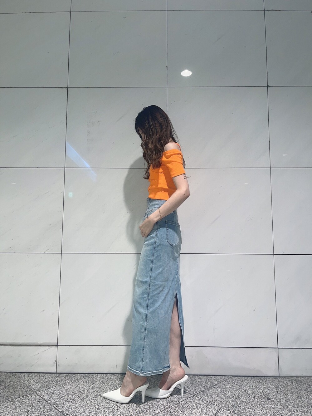 オレンジ系のTシャツ/カットソー、ブルー系のデニムスカート、ホワイト系のパンプスを着用したレディースの夏コーディネートの2枚目の写真