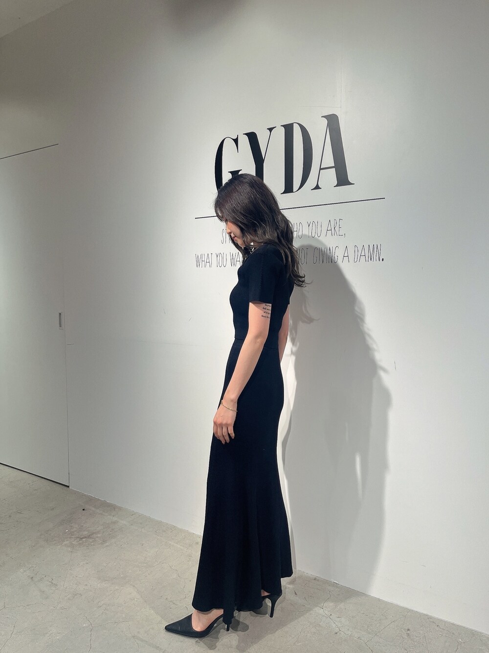 ブラック系のニット/セーター、ブラック系のスカート、ブラック系のパンプスを着用したレディースの夏コーディネートの2枚目の写真