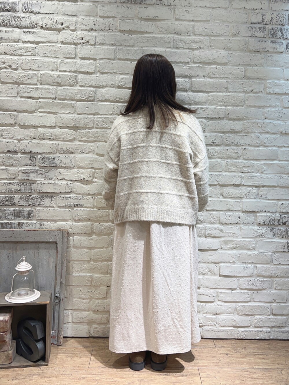 ホワイト系のカーディガン/ボレロ、ホワイト系のワンピース、ベージュ系のドレスシューズを着用したレディースの冬コーディネートの3枚目の写真