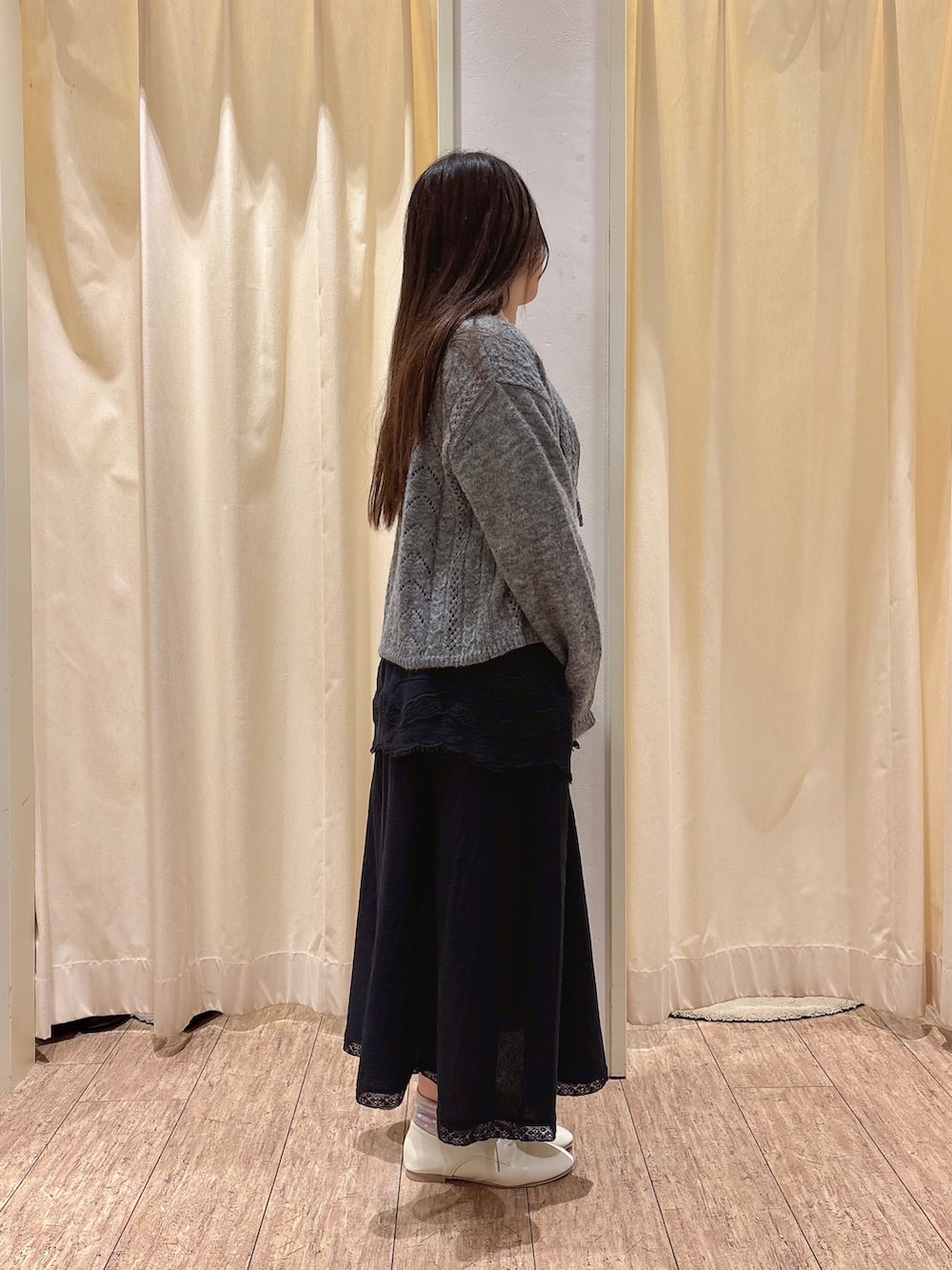 ベージュ系のハンドバッグ、グレー系のカーディガン/ボレロ、ホワイト系のニット/セーターを着用したレディースの秋コーディネートの2枚目の写真