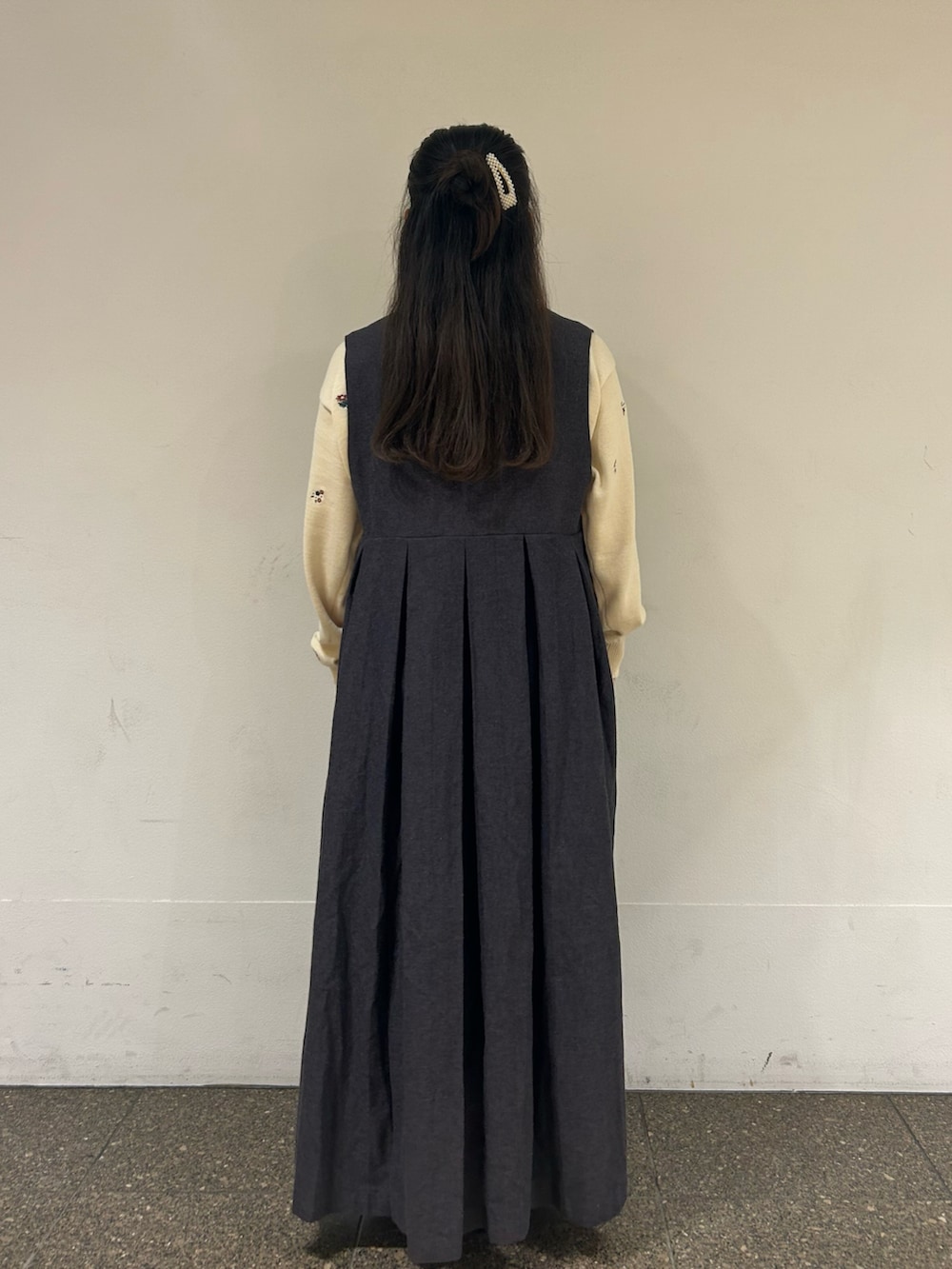 グレー系のワンピース、ホワイト系のカーディガン/ボレロ、ブラック系のドレスシューズを着用したレディースの秋コーディネートの3枚目の写真