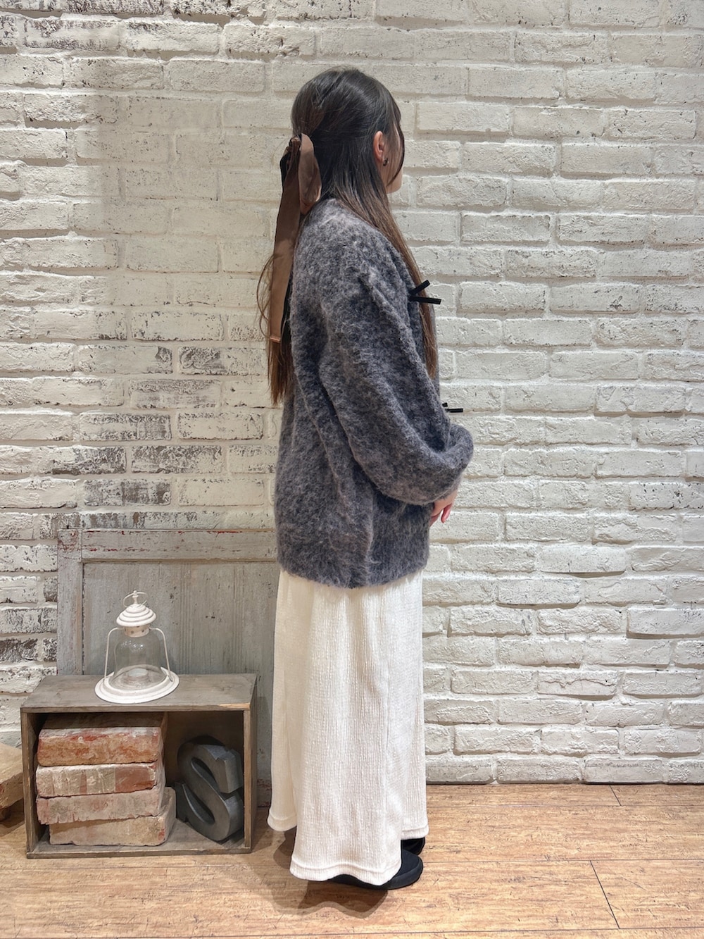 グレー系のニット/セーター、ホワイト系のスカートを着用したレディースの冬コーディネートの2枚目の写真