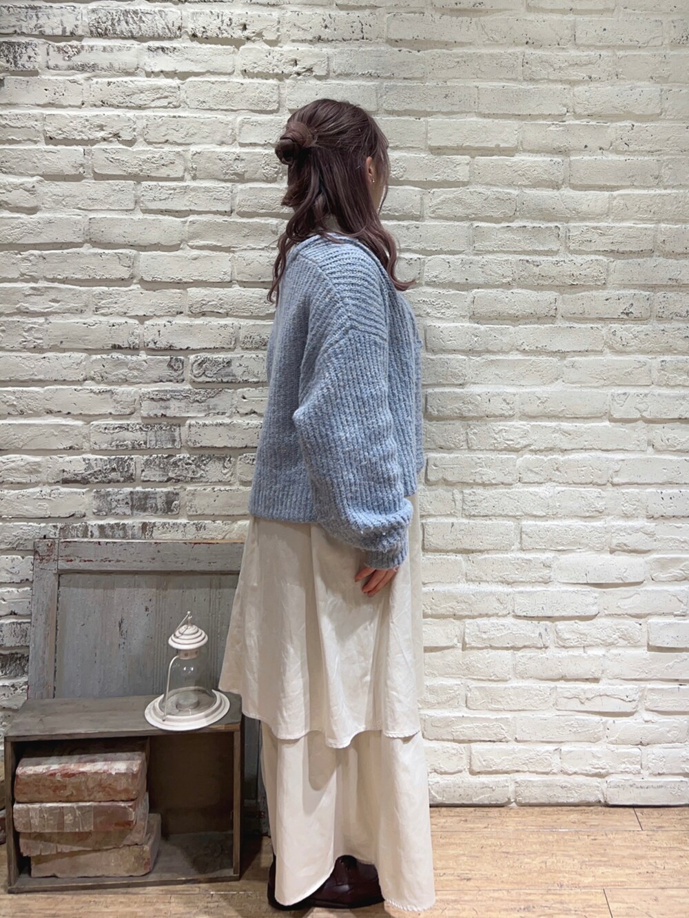 ホワイト系のスカート、ホワイト系のニット/セーター、ブルー系のカーディガン/ボレロを着用したレディースの冬コーディネートの2枚目の写真