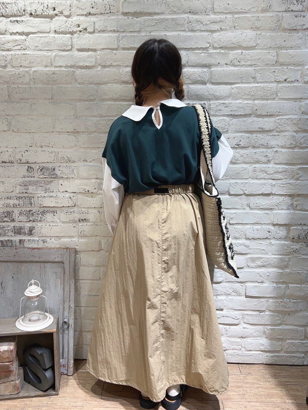 ベージュ系のハンドバッグ、ベージュ系のスカート、グリーン系のTシャツ/カットソーを着用したレディースの秋コーディネートの3枚目の写真