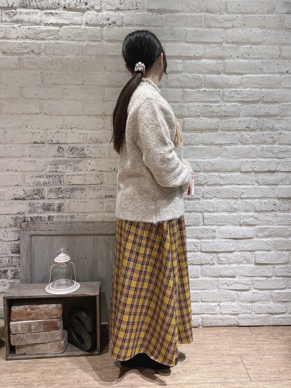 ブラウン系のブーツ、ベージュ系のニット/セーター、イエロー系のスカートを着用したレディースの冬コーディネートの2枚目の写真