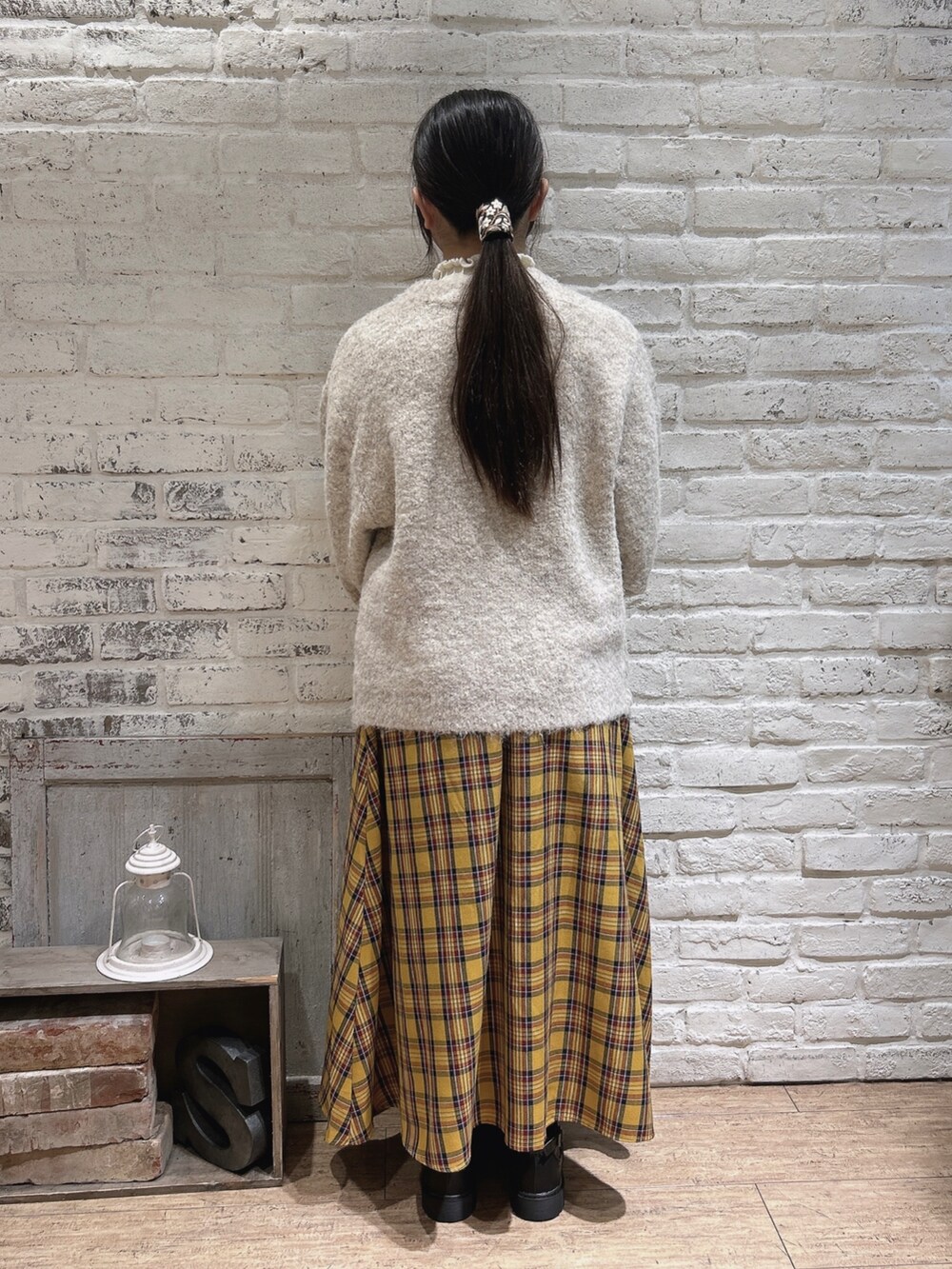 ブラウン系のブーツ、ベージュ系のニット/セーター、イエロー系のスカートを着用したレディースの冬コーディネートの3枚目の写真