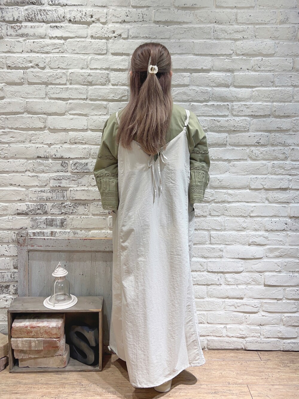 シルバー系のハンドバッグ、グリーン系のTシャツ/カットソー、ホワイト系のサンダルを着用したレディースの夏コーディネートの3枚目の写真