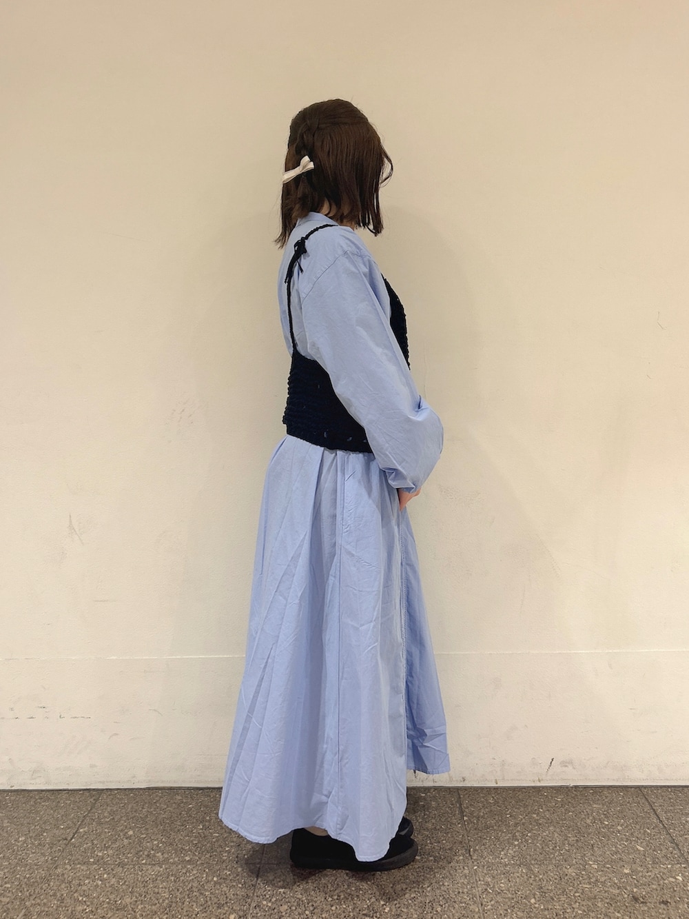 ブラック系のベスト、ブルー系のワンピースを着用したレディースの春コーディネートの2枚目の写真