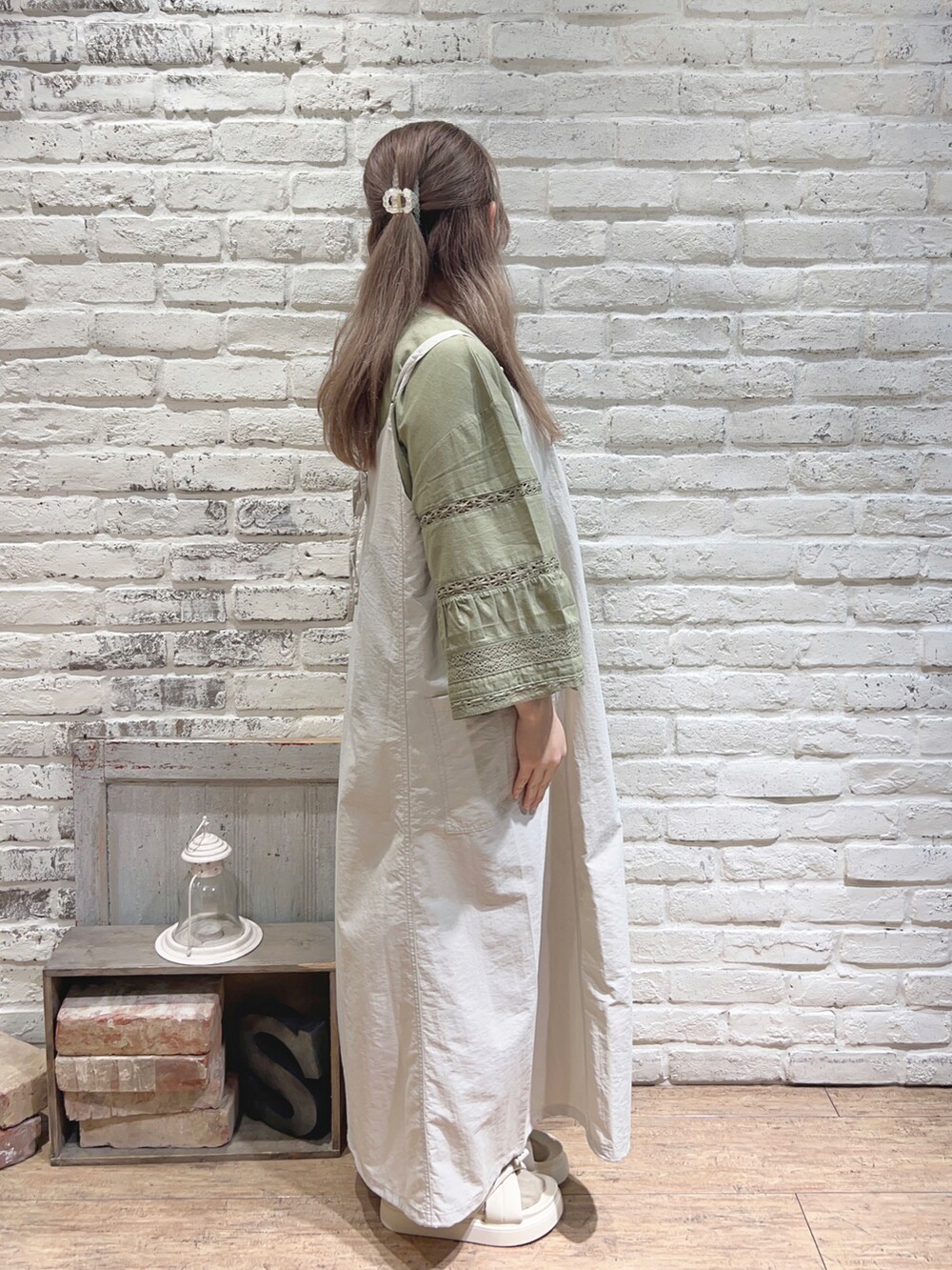 シルバー系のハンドバッグ、グリーン系のTシャツ/カットソー、ホワイト系のサンダルを着用したレディースの夏コーディネートの2枚目の写真