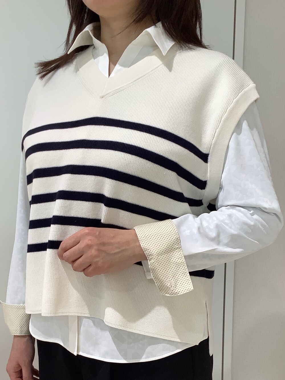 ホワイト系のベスト、イエロー系のビジネスシャツを着用したレディースの春コーディネートの2枚目の写真