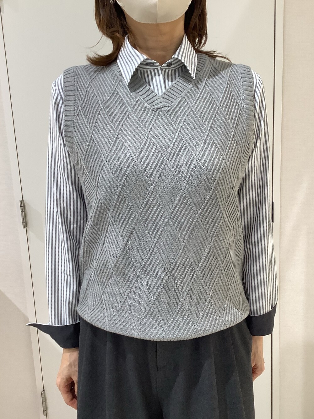 グレー系のベスト、グレー系のビジネスシャツを着用したレディースの秋コーディネートの2枚目の写真