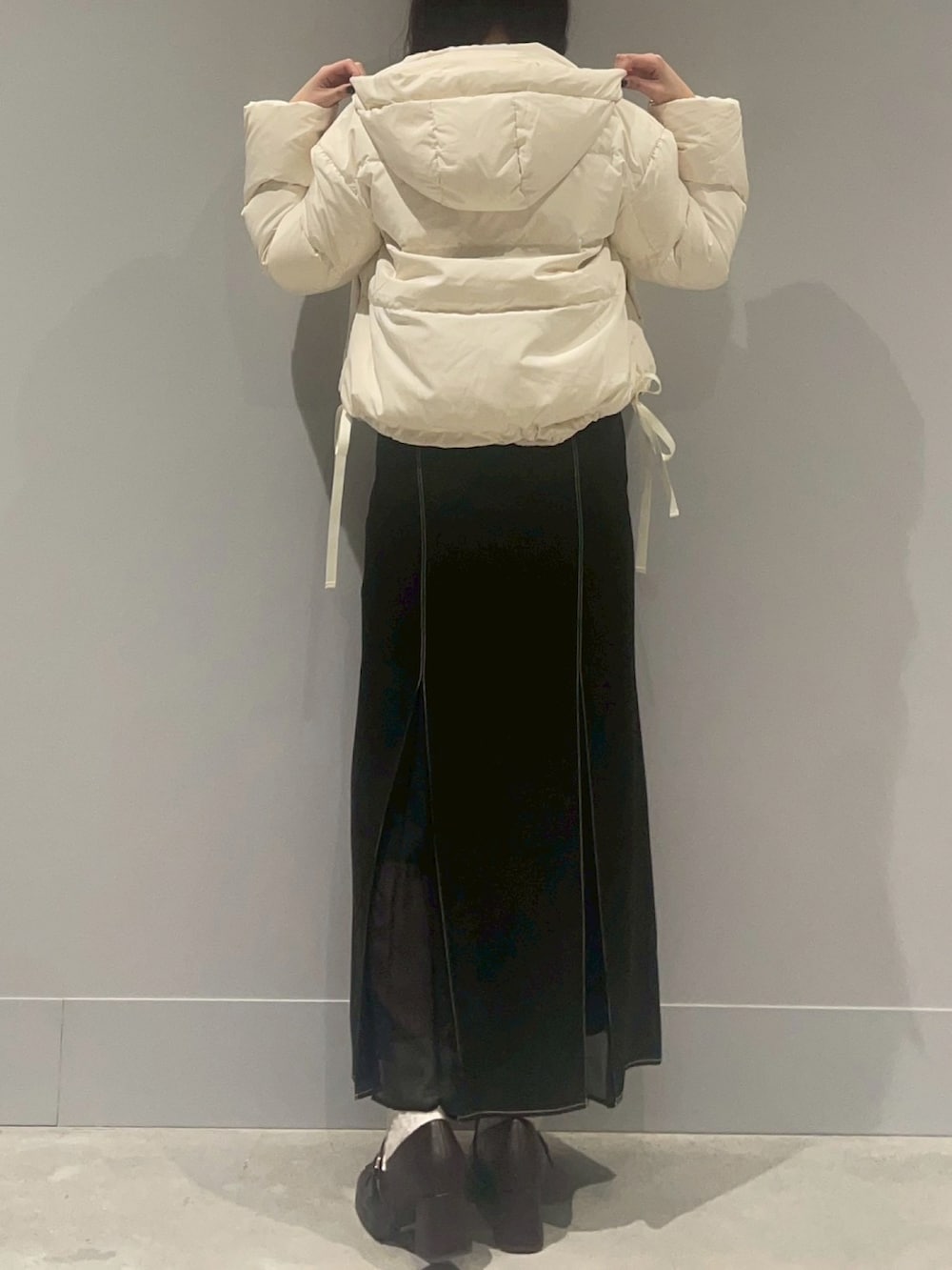 レッド系のカーディガン/ボレロ、ホワイト系のダウンジャケット/コート、ブラック系のスカートを着用したレディースの冬コーディネートの3枚目の写真