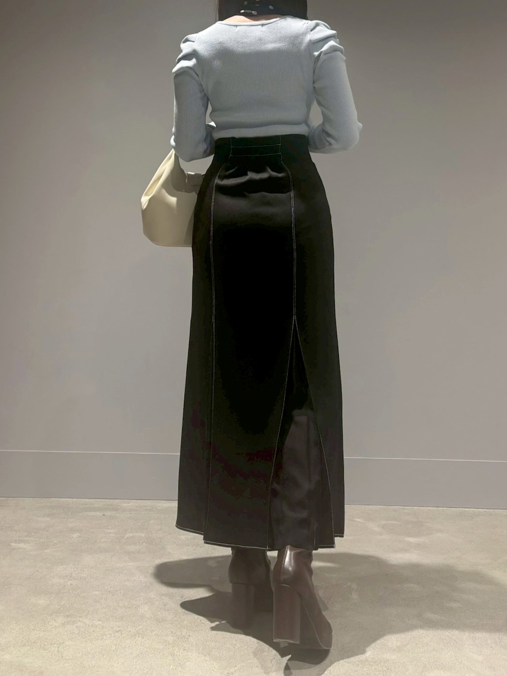 ブラック系のスカート、ホワイト系のニット/セーター、ホワイト系のハンドバッグを着用したレディースの冬コーディネートの3枚目の写真