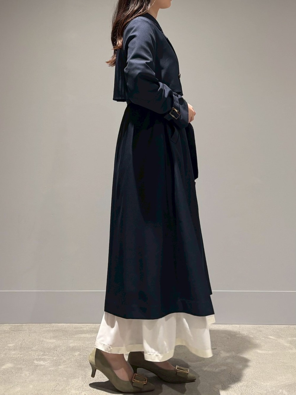 ブルー系のトレンチコート、ホワイト系のスカートを着用したレディースの春コーディネートの2枚目の写真