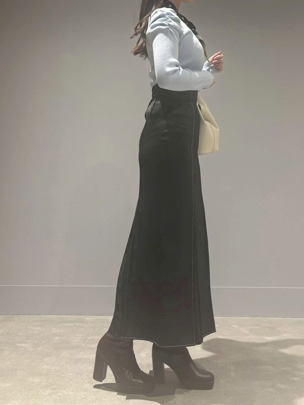 ブラック系のスカート、ホワイト系のニット/セーター、ホワイト系のハンドバッグを着用したレディースの冬コーディネートの2枚目の写真