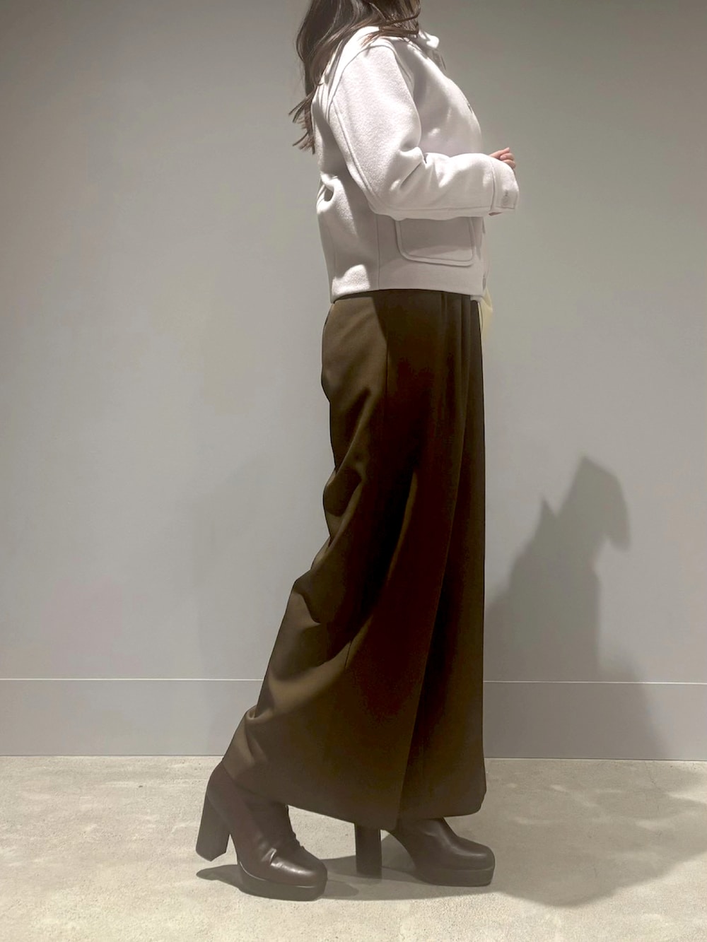 ブラウン系のつなぎ/オールインワン、グレー系のチェスターコート、ホワイト系のハンドバッグを着用したレディースの冬コーディネートの2枚目の写真