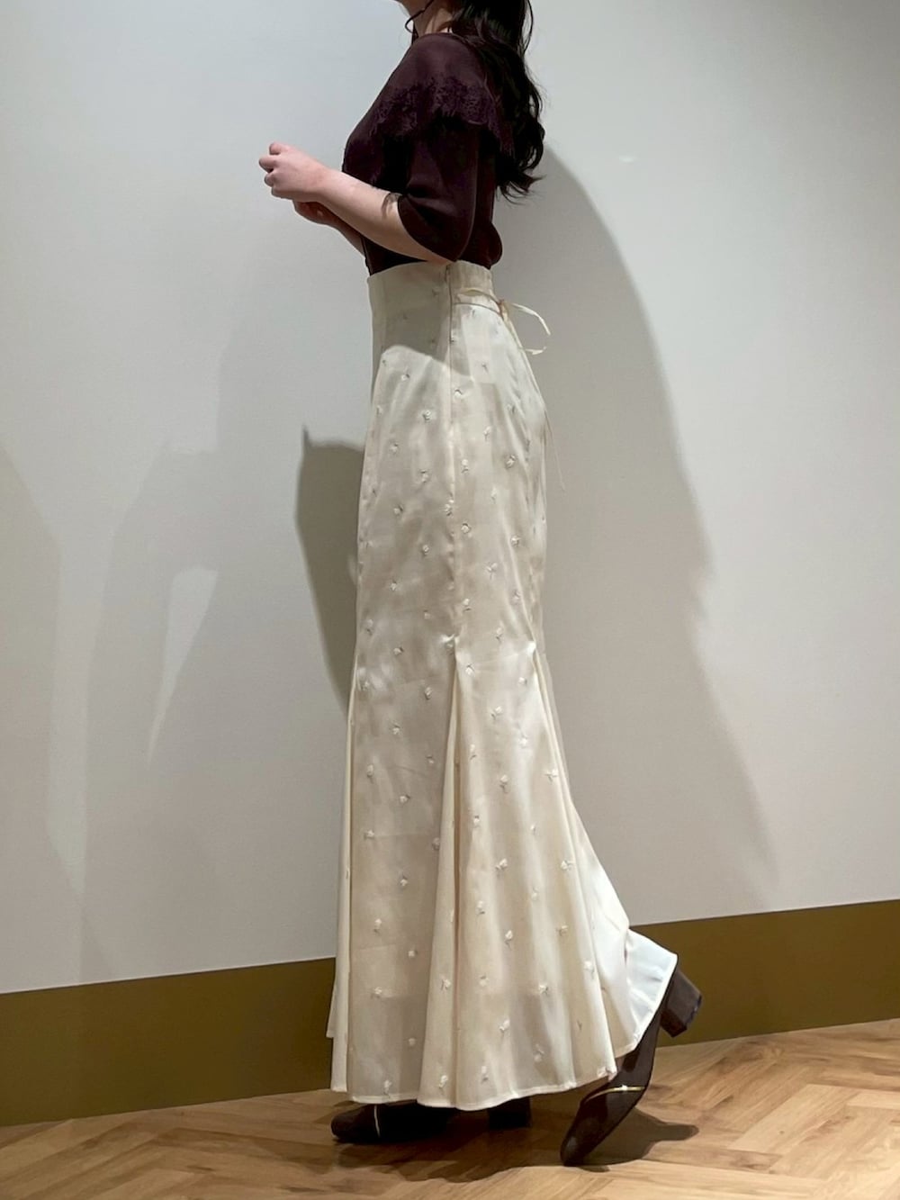 イエロー系のスカート、ブラウン系のニット/セーターを着用したレディースの春コーディネートの2枚目の写真