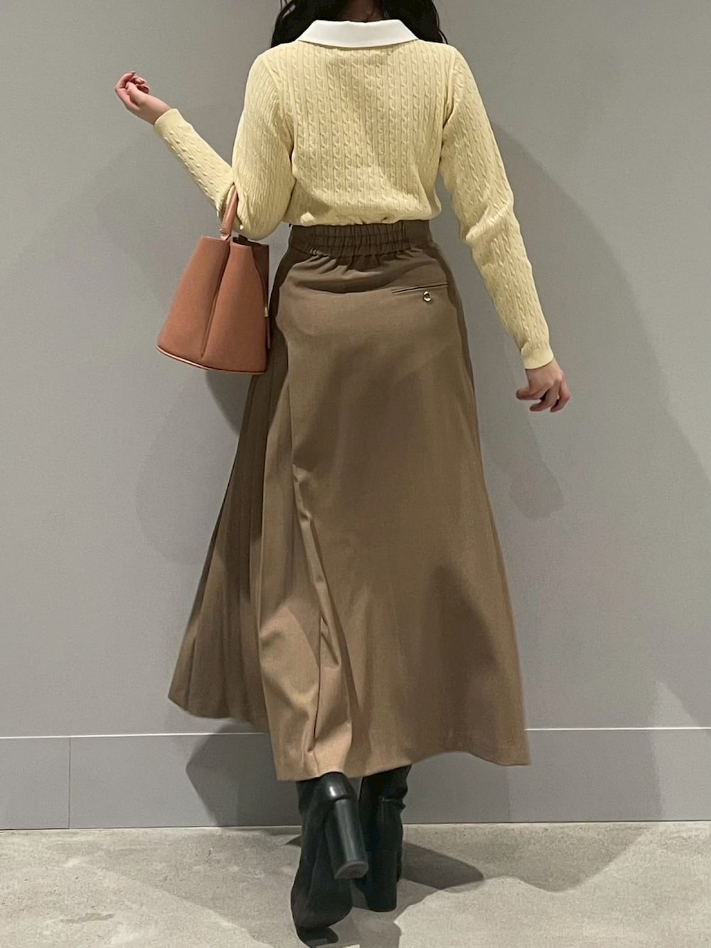 イエロー系のカーディガン/ボレロ、ブラウン系のスカート、ベージュ系のハンドバッグを着用したレディースの冬コーディネートの3枚目の写真
