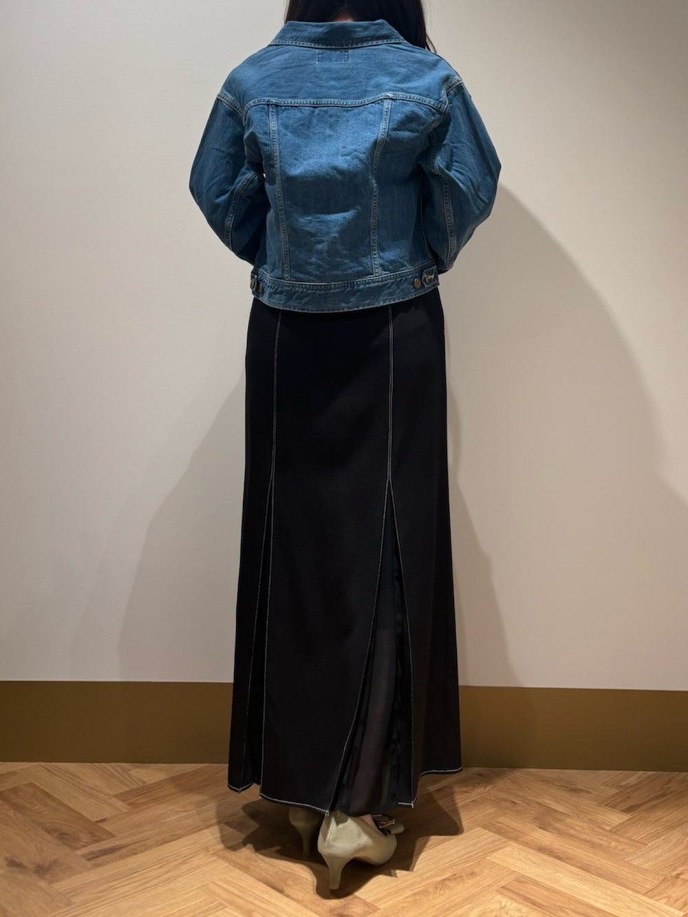 ブルー系のデニムジャケット、ブラック系のスカート、イエロー系のニット/セーターを着用したレディースの春コーディネートの3枚目の写真