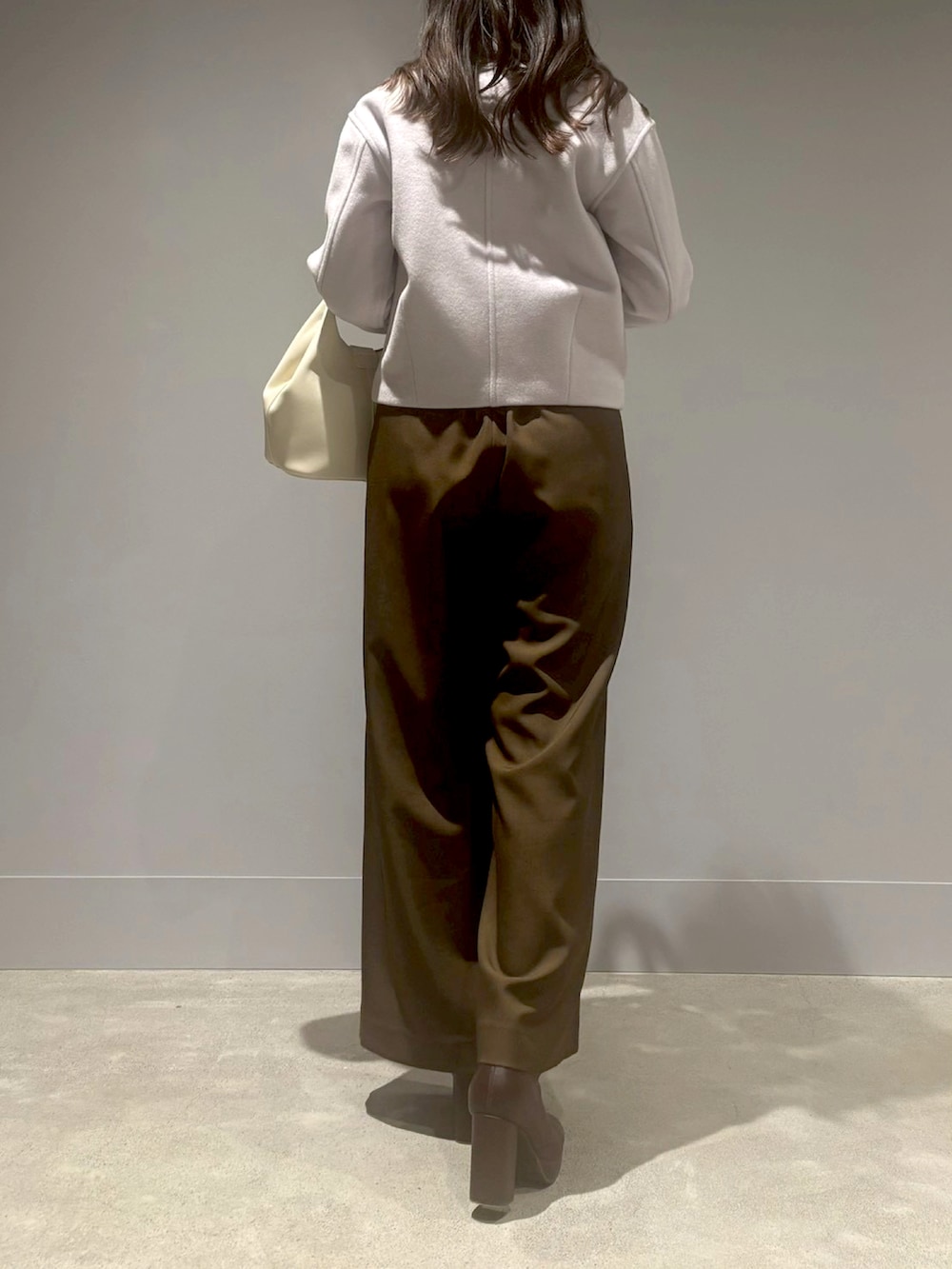 ブラウン系のつなぎ/オールインワン、グレー系のチェスターコート、ホワイト系のハンドバッグを着用したレディースの冬コーディネートの3枚目の写真