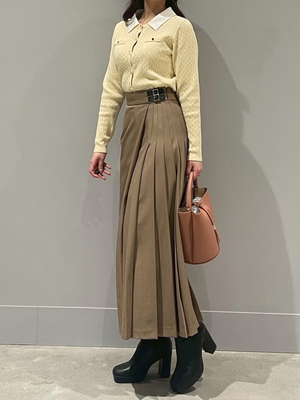 イエロー系のカーディガン/ボレロ、ブラウン系のスカート、ベージュ系のハンドバッグを着用したレディースの冬コーディネートの2枚目の写真