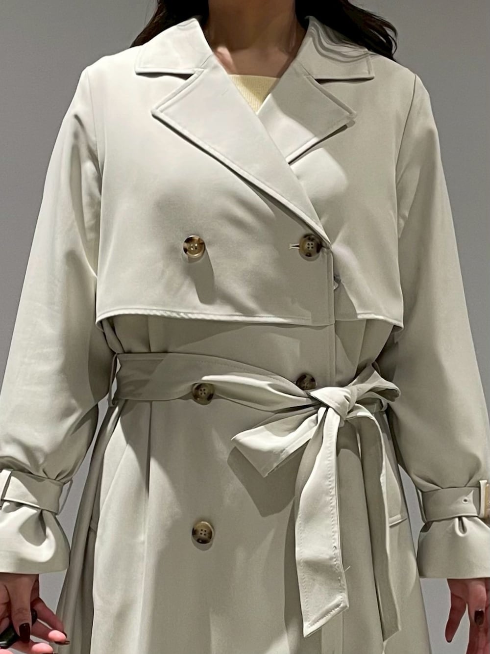 ブラウン系のスカート、イエロー系のニット/セーター、グリーン系のトレンチコートを着用したレディースの冬コーディネートの4枚目の写真