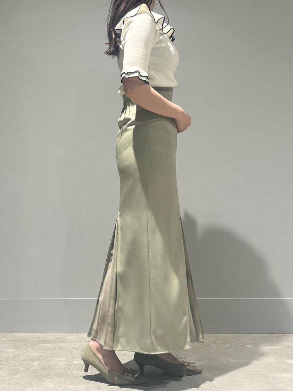 グリーン系のスカート、ホワイト系のニット/セーターを着用したレディースの春コーディネートの3枚目の写真