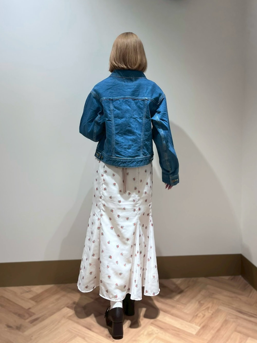 ブルー系のデニムジャケット、ピンク系のニット/セーター、ホワイト系のスカートを着用したレディースの春コーディネートの3枚目の写真