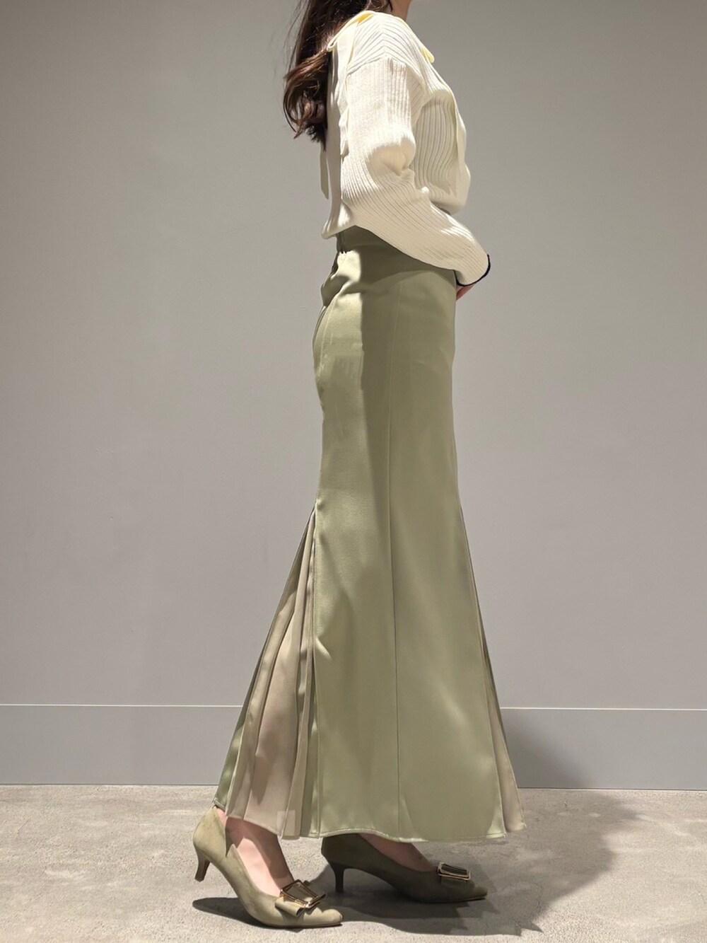 グリーン系のスカート、ブルー系のニット/セーターを着用したレディースの春コーディネートの2枚目の写真