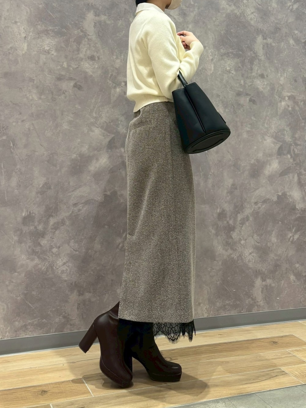 ホワイト系のカーディガン/ボレロ、ブラウン系のスカート、ベージュ系のショルダーバッグを着用したレディースの冬コーディネートの2枚目の写真