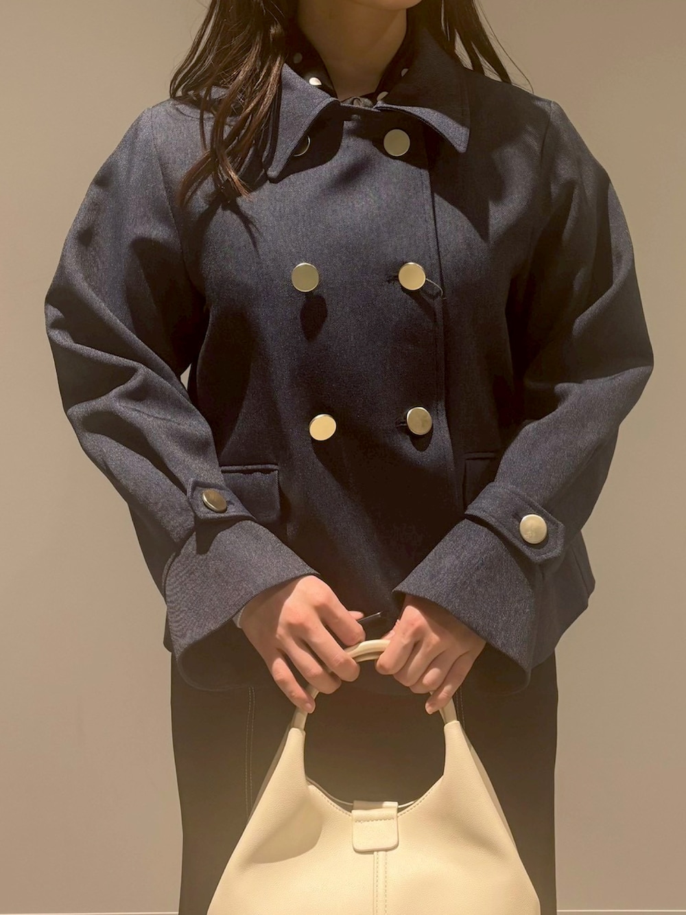 ブラック系のスカート、ベージュ系のブルゾン、ホワイト系のハンドバッグを着用したレディースの冬コーディネートの4枚目の写真