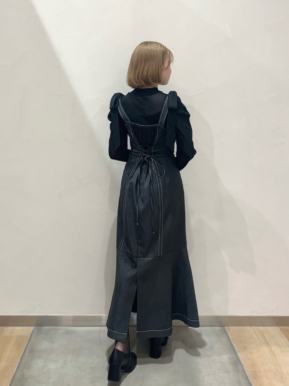 ブラック系のジャンパースカート、ブラック系のTシャツ/カットソーを着用したレディースの春コーディネートの2枚目の写真